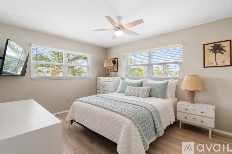 A bedroom with a bed, nightstand, and a ceiling fan.