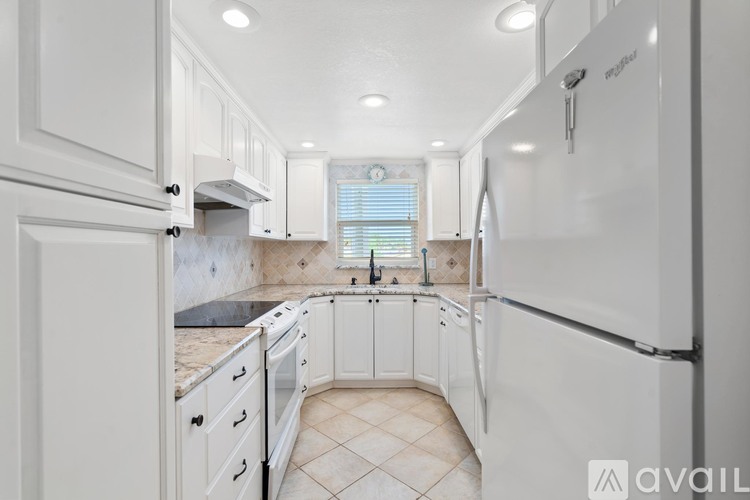 A kitchen with white cabinets and appliances, including a refrigerator, is available for rent.