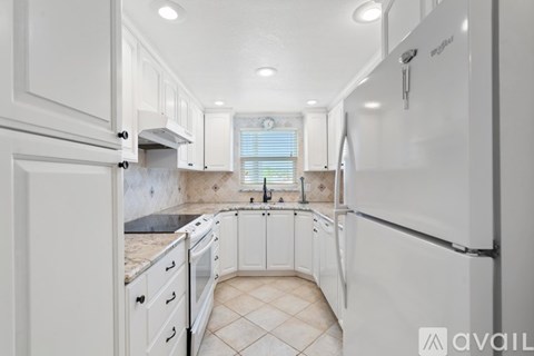 A kitchen with white cabinets and appliances, including a refrigerator, is available for rent.