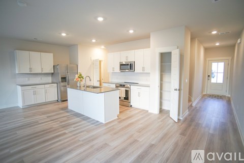 A kitchen with white cabinets and a wooden floor.