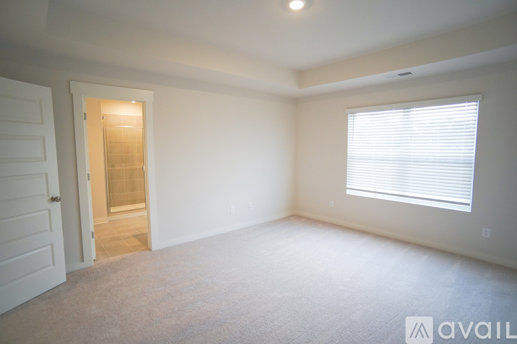 A room with a carpeted floor and a window with blinds.