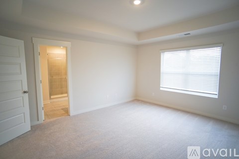 A room with a carpeted floor and a window with blinds.