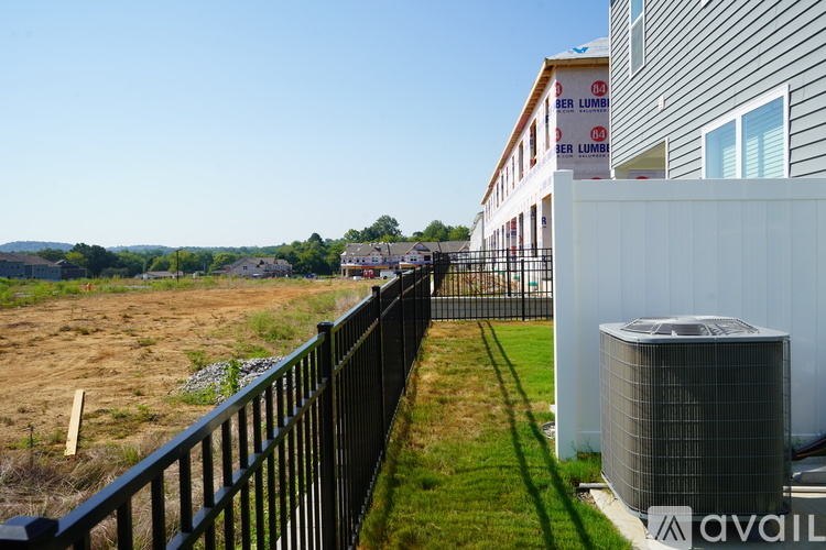 A black fence with a green lawn in front of a building with the word "BERLUM" on it.