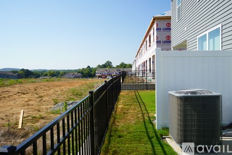 A black fence with a green lawn in front of a building with the word "BERLUM" on it.