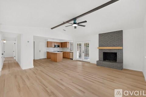 A spacious living room with a fireplace and a ceiling fan.