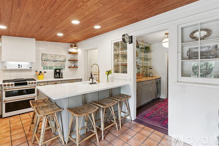 A kitchen with a white counter top and wooden bar stools.