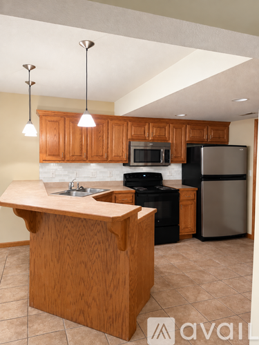 A kitchen with wooden cabinets and a black refrigerator.
