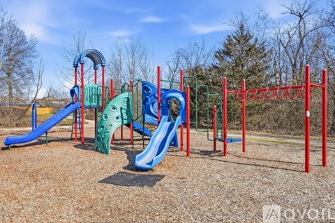 A playground with a blue slide and red poles.