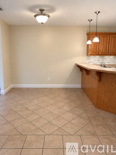A kitchen area with tile flooring and wooden cabinets.