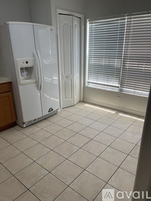 A white refrigerator in a kitchen with a tile floor.