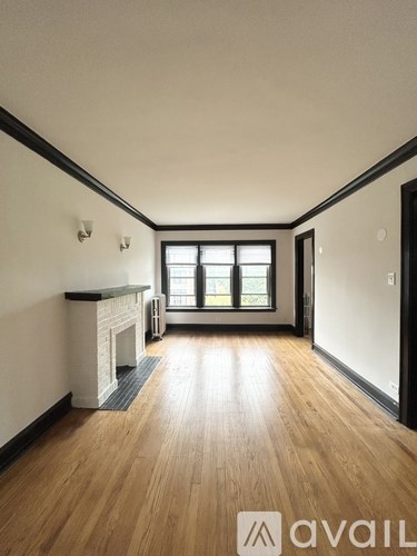 A room with wooden floors and a fireplace with a window in the background.