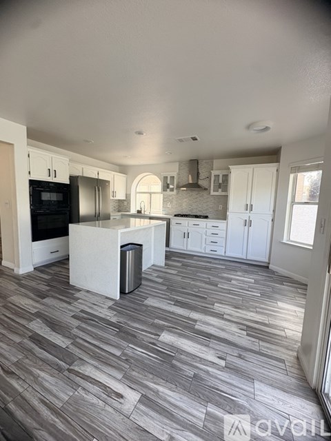A kitchen with a tiled floor and a trash bin.