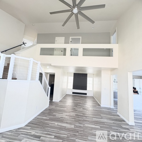 A spacious living room with a staircase and a ceiling fan.