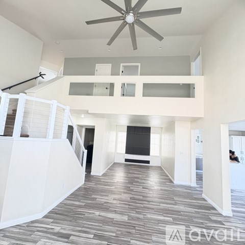 A spacious living room with a staircase and a ceiling fan.