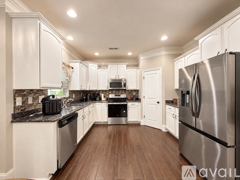 A modern kitchen with white cabinets and stainless steel appliances.