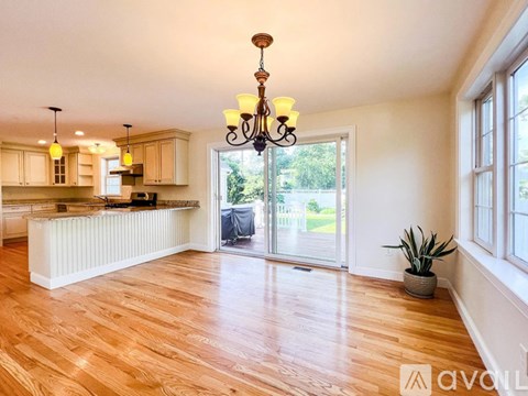 A well-lit kitchen with wooden floors and a chandelier.
