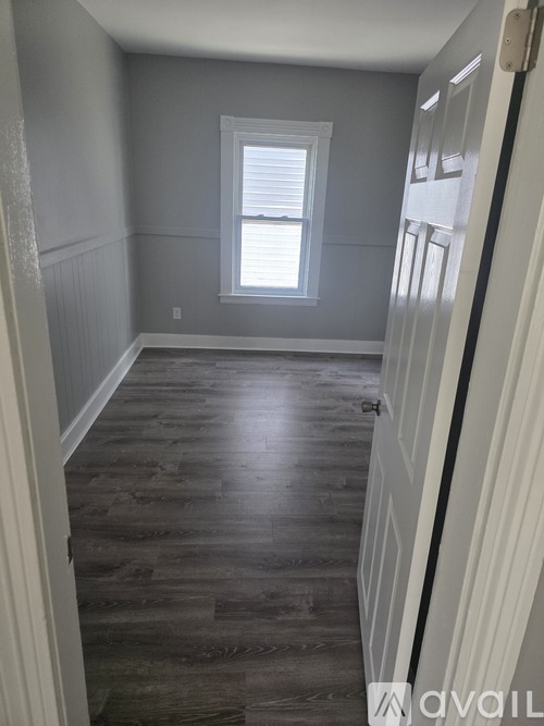 A hallway with wood flooring and white walls.