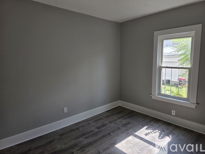 A room with a window and wooden flooring.