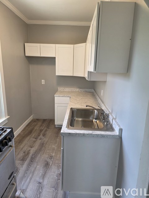 A kitchen with a sink, stove and cabinets.