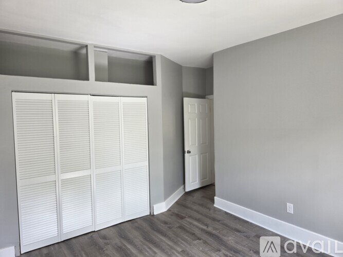 A room with a white door and a grey wall.