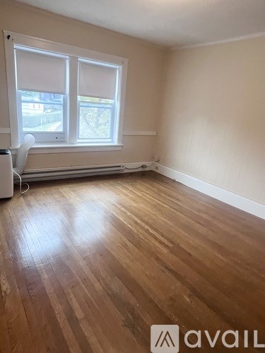 A room with wooden flooring and a window with blinds.
