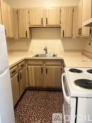 A kitchen with wooden cabinets and a white fridge.