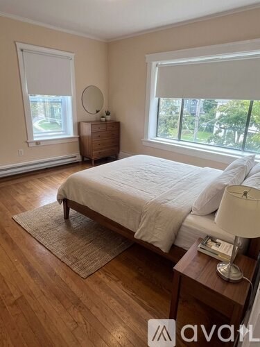 A bedroom with a bed, nightstand, and window.