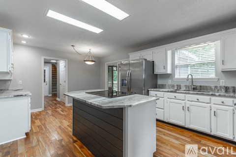 A kitchen with white cabinets and a wooden floor.