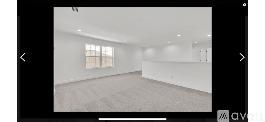 A spacious room with a window and carpeted floor.