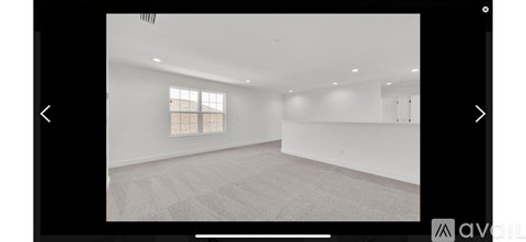 A spacious room with a window and carpeted floor.