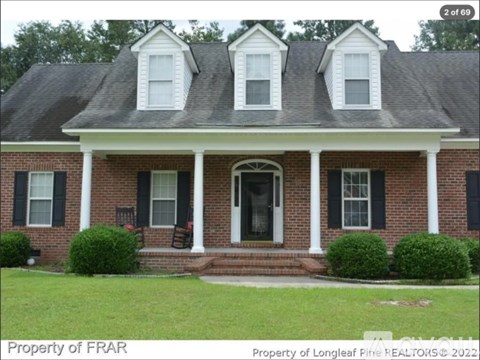 A brick house with a black roof and white trim.