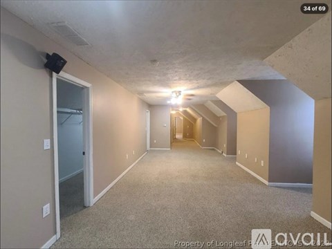 A spacious room with a door on the left and a hallway leading to another room on the right.