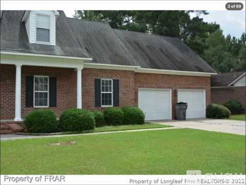 A brick house with a white garage door and black shutters.