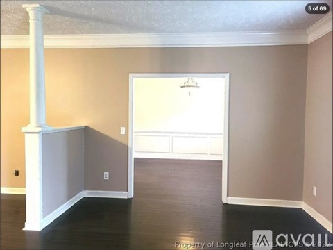A room with a white column and a door leading to another room.