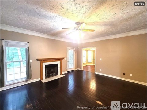 A living room with a fireplace and a ceiling fan.
