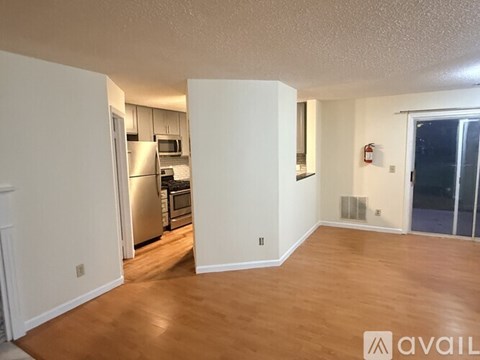A kitchen with white cabinets and a stainless steel refrigerator is visible from the living room.