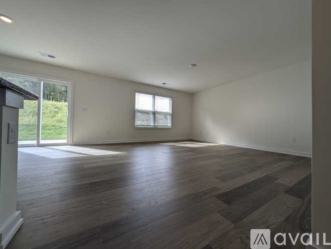A spacious room with wooden flooring and a large window.