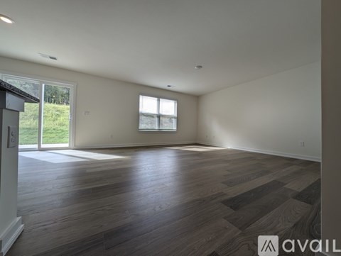 A spacious room with wooden flooring and a large window.