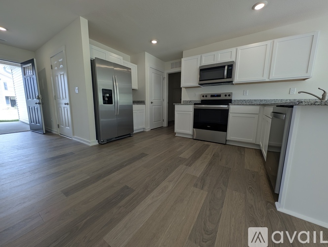 A kitchen with white cabinets and a wooden floor.