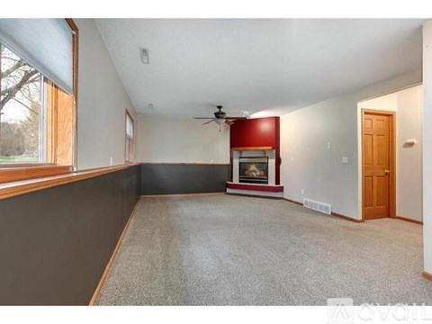 A spacious living room with a fireplace and a ceiling fan.