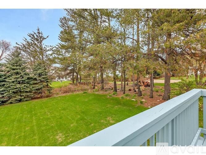 A view from a balcony overlooking a green lawn and trees.