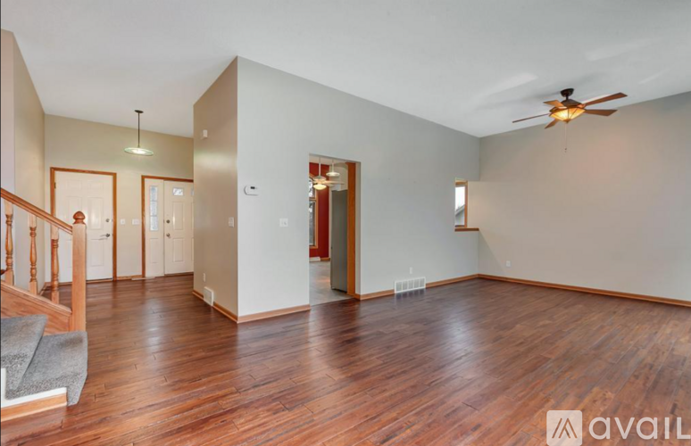 A spacious room with wooden floors and a ceiling fan.
