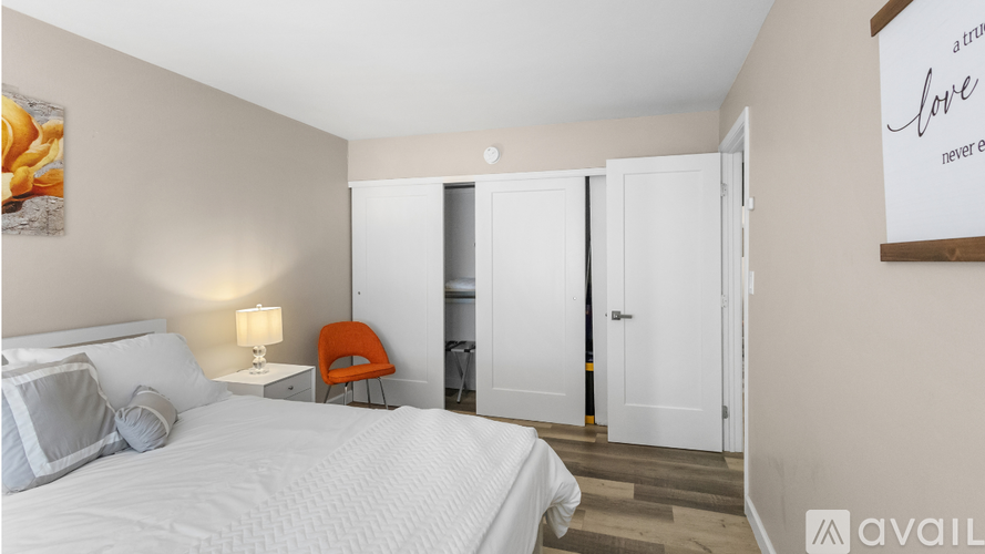 A bedroom with a white bed and a red chair.