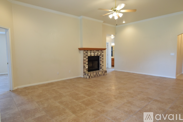 A living room with a fireplace and a ceiling fan.