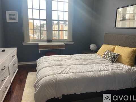 A bedroom with a large bed and a window with a view of the city.