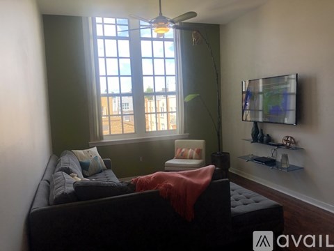 A living room with a black couch and a window.