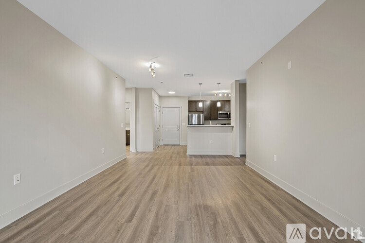 A spacious room with wooden flooring and white walls.
