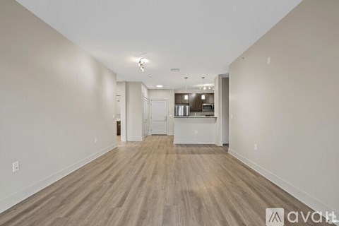 A spacious room with wooden flooring and white walls.
