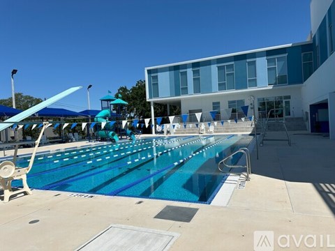 A large outdoor swimming pool with sun loungers and a building in the background.