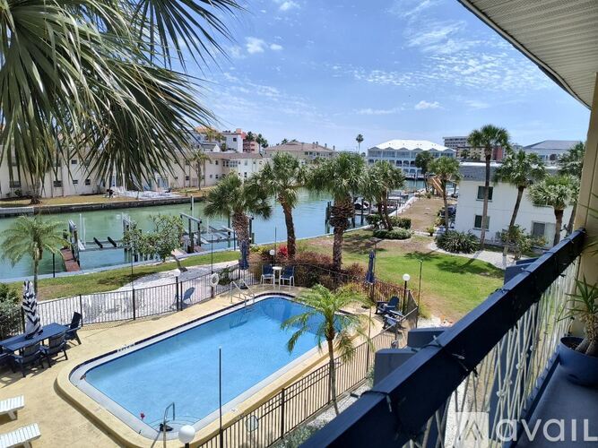 A pool surrounded by palm trees and a fence.